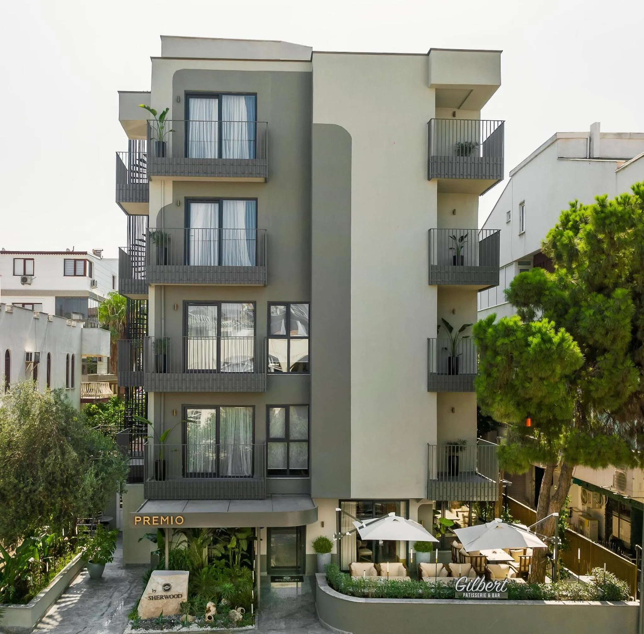 Facade d'un bâtiment moderne avec des balcons et une terrasse ombragée.