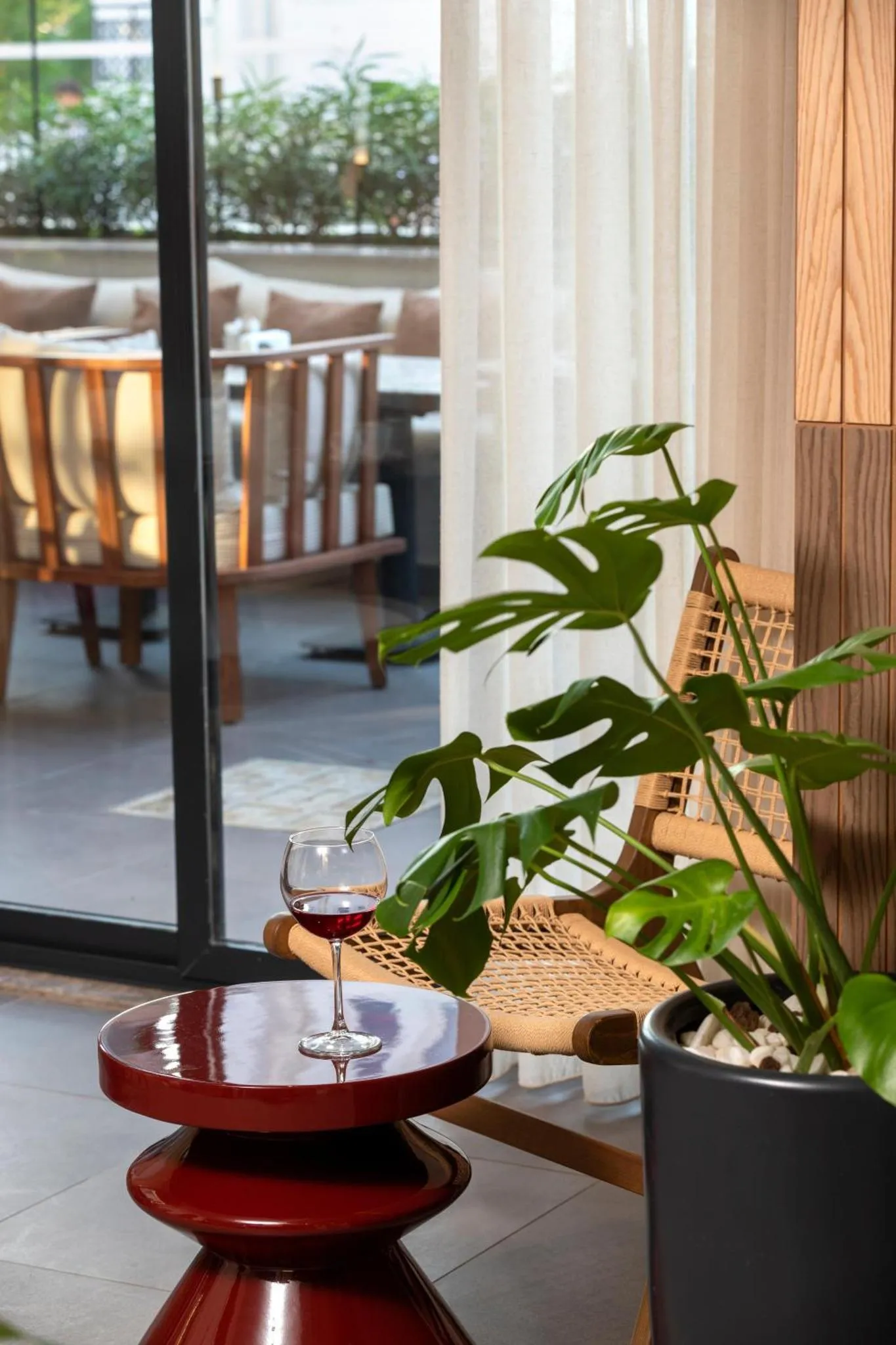 Un verre de vin rouge repose sur une table basse devant une terrasse aménagée.