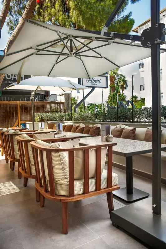 Terrasse ombragée avec mobilier de jardin et tables.