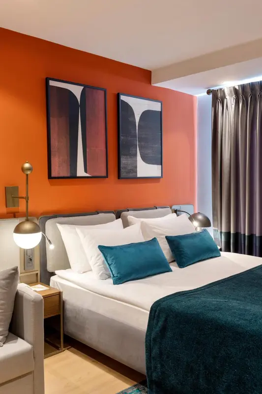 Une chambre avec un lit double et des tableaux décoratifs au mur.