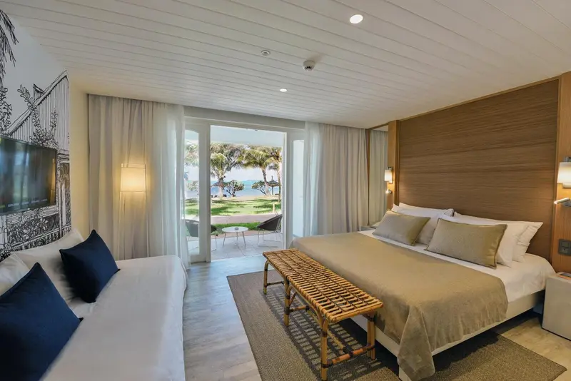 Une chambre lumineuse s'ouvre sur une vue verdoyante et la mer.