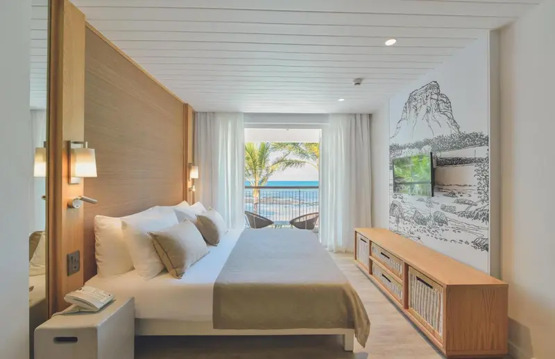 Une chambre lumineuse avec un grand lit donnant sur une vue mer.