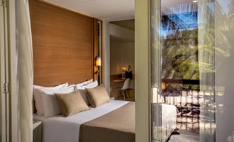 Une chambre lumineuse avec un grand lit et une vue sur la végétation.