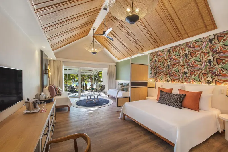 Une chambre lumineuse avec un lit king-size et un coin salon.