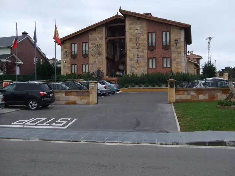 Façade d'un bâtiment avec un parking et des drapeaux.