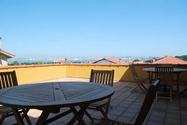 Terrasse avec tables et chaises offrant une vue sur la mer et les environs.