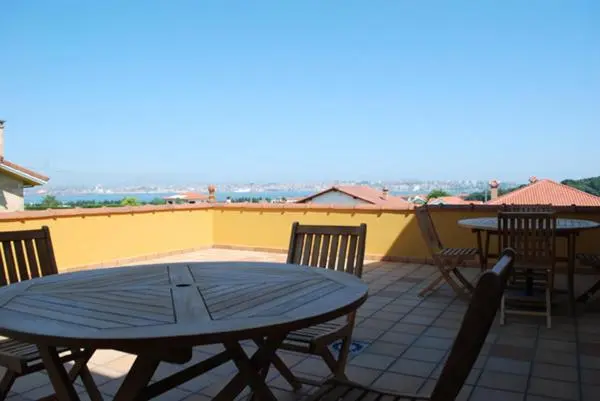 Terrasse avec tables et chaises offrant une vue sur la mer et les environs.