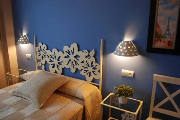 Un lit avec une tete de lit en fer forgé floral dans une chambre aux murs bleus.