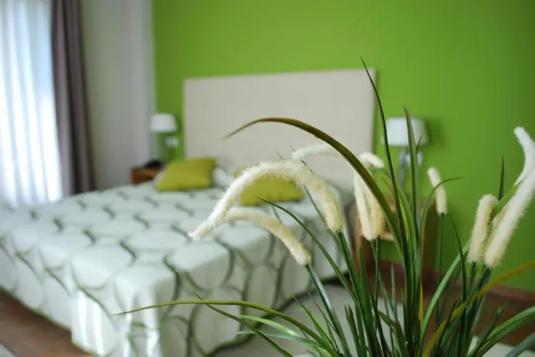Une chambre lumineuse avec un lit recouvert d'une courtepointe blanche et de coussins verts.