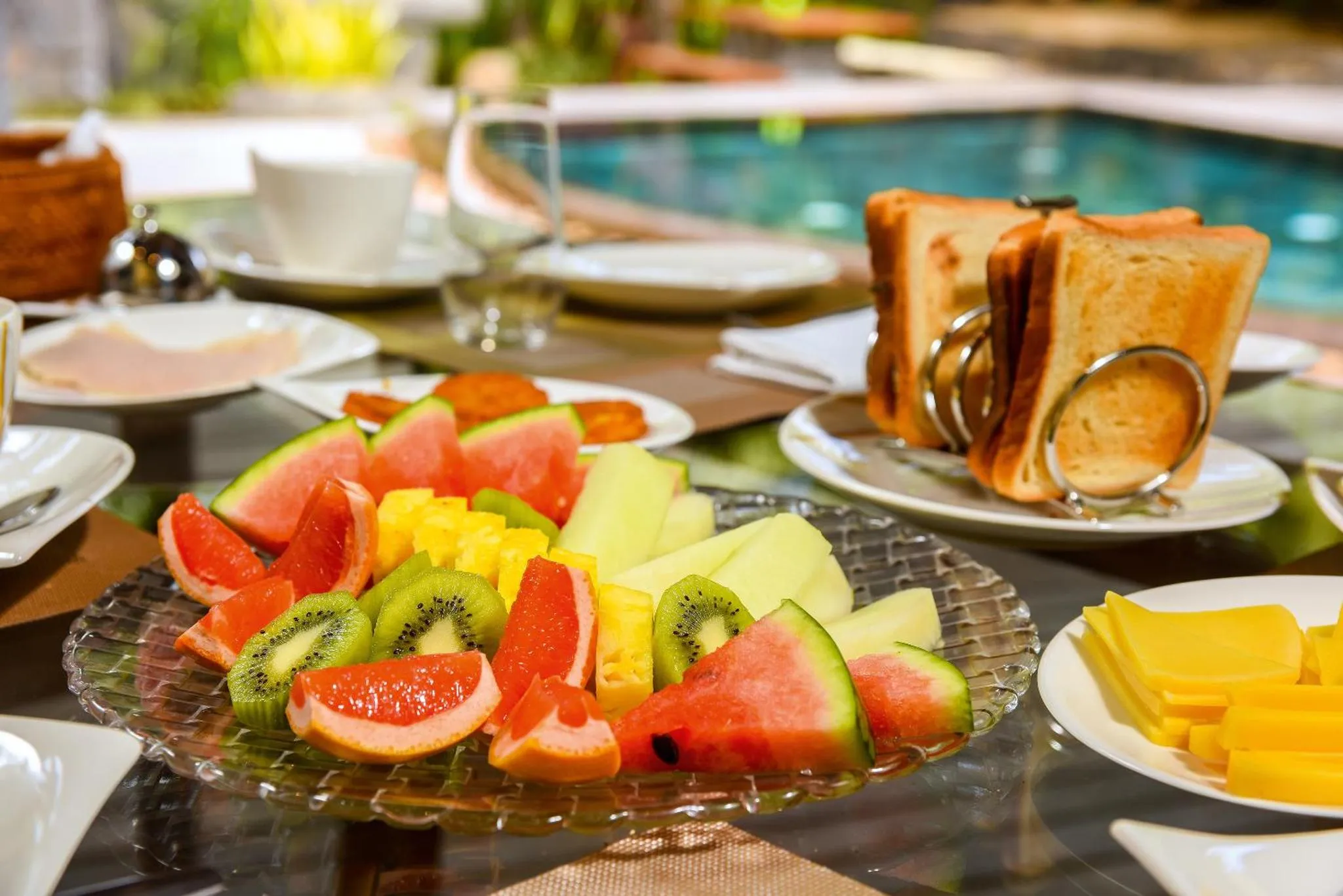 Une table est dressée avec des fruits frais, des viennoiseries et des boissons.
