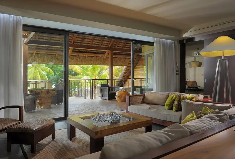 Espace de détente intérieur avec canapés et table basse donnant sur une terrasse.