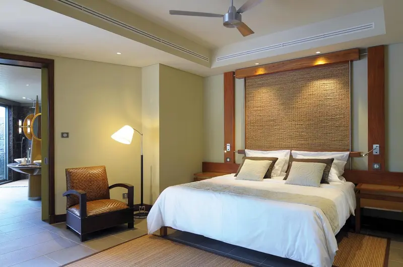 Une chambre lumineuse avec un grand lit et un fauteuil.