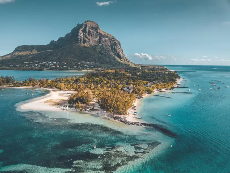 Vue aérienne d'une péninsule tropicale avec une montagne en arrière-plan et des bateaux dans la baie.