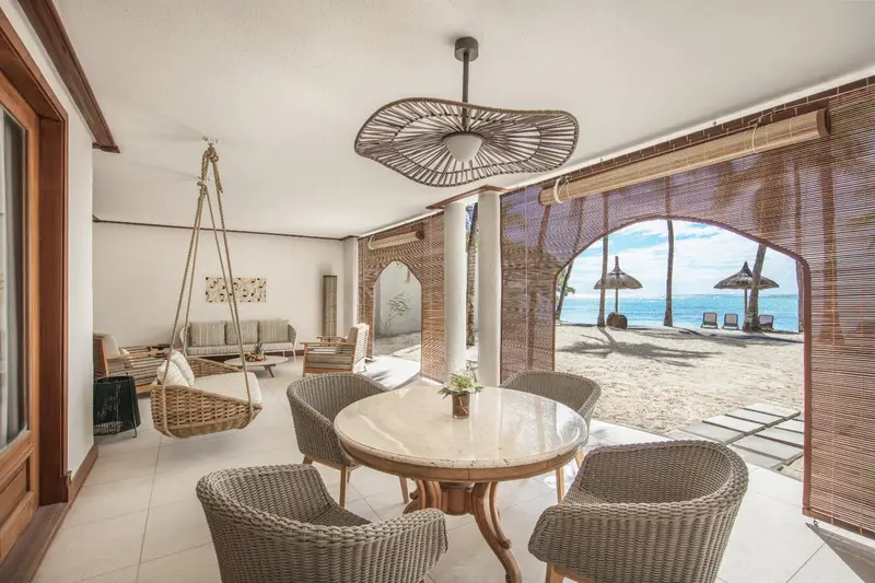 Espace de détente intérieur avec table et chaises, donnant sur une plage ensoleillée.