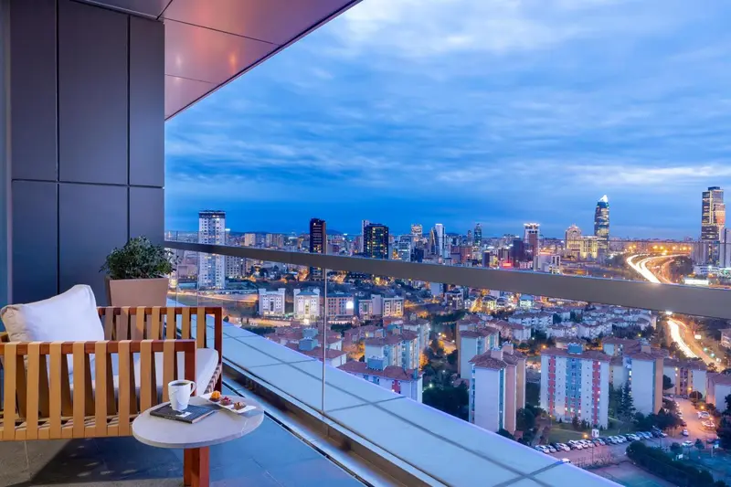 Terrasse avec mobilier en bois et vue sur une ville illuminée.