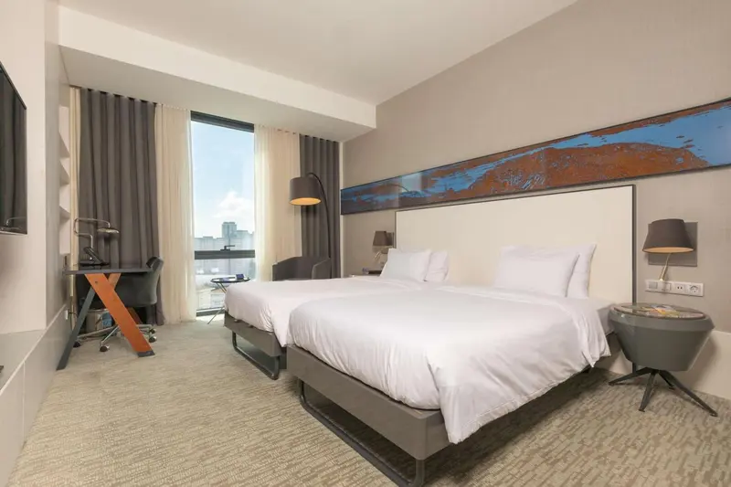 Chambre lumineuse avec un grand lit et un espace de travail.