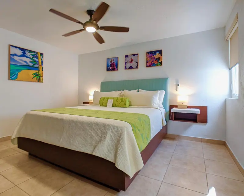 Une chambre lumineuse avec un grand lit recouvert d'une couette verte et blanche.
