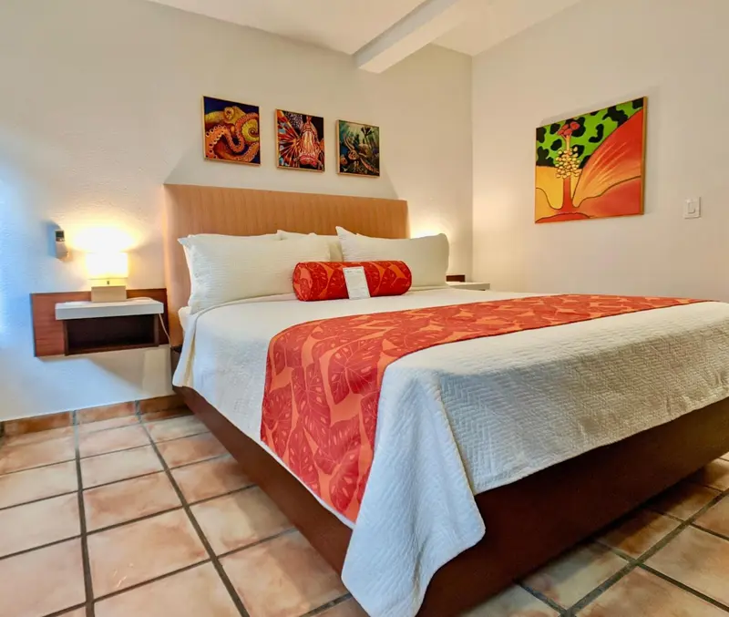 Une chambre lumineuse avec un grand lit recouvert d'une courtepointe blanche et rouge.