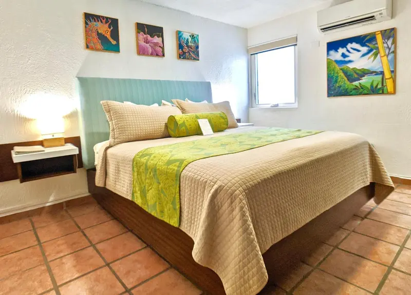 Une chambre lumineuse avec un grand lit recouvert d'une courtepointe.