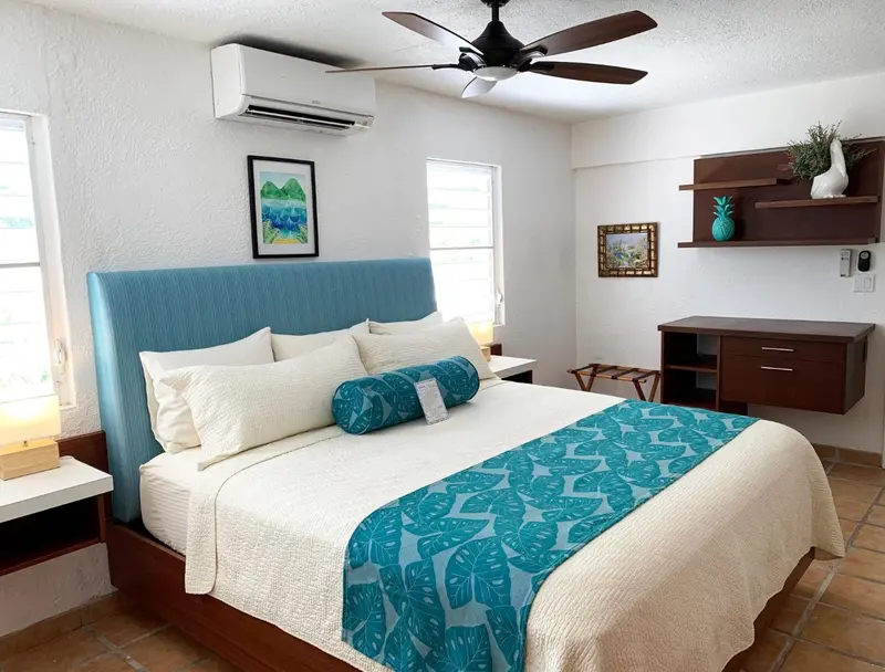 Une chambre lumineuse avec un grand lit recouvert d'une courtepointe blanche et turquoise.