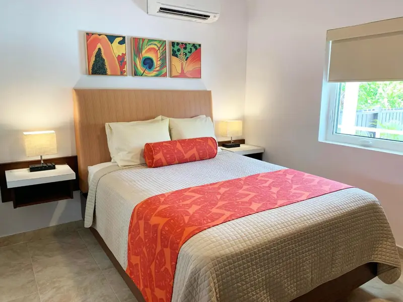 Une chambre lumineuse avec un grand lit et des tableaux colorés.