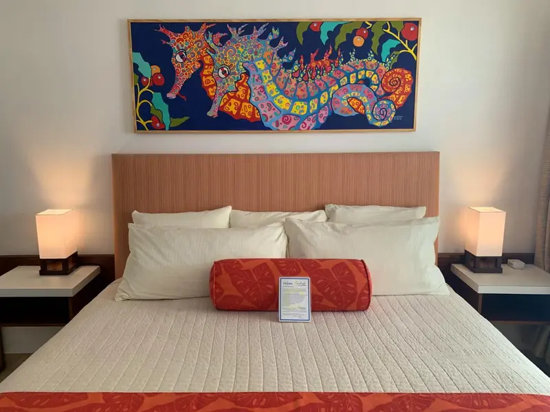 Une chambre avec un grand lit et une décoration murale colorée.
