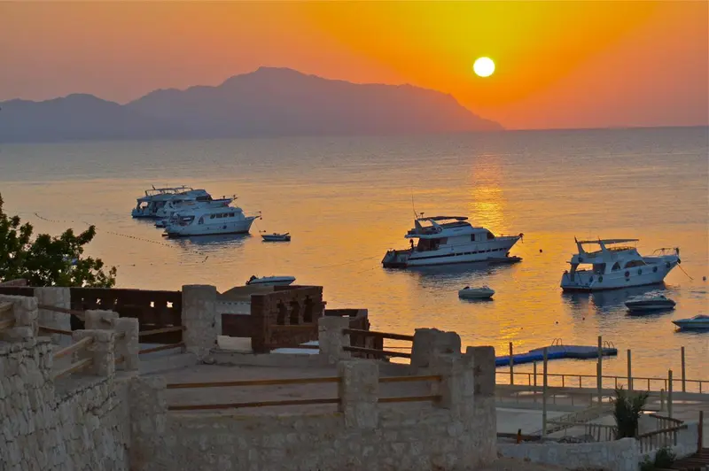 Coucher de soleil sur la mer avec des bateaux amarrés au large.