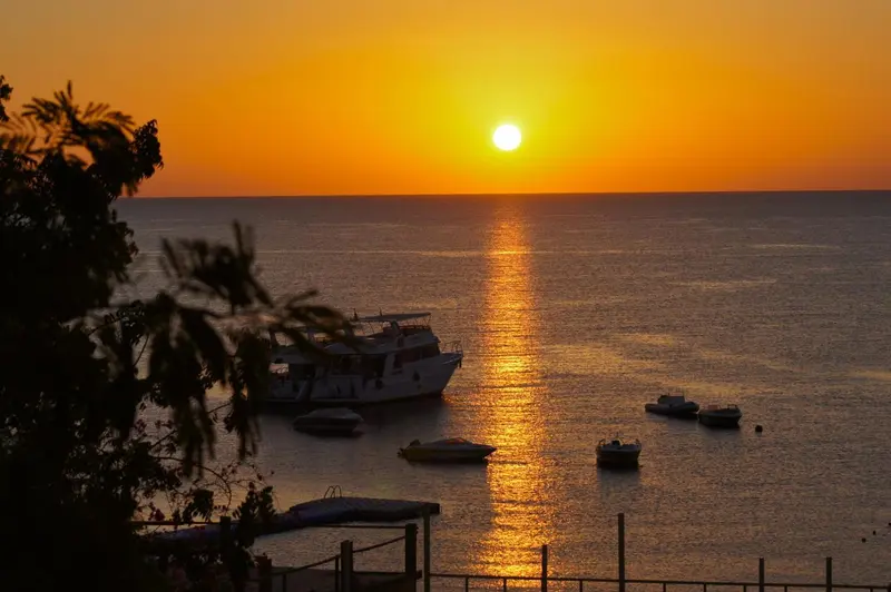 Le soleil se couche sur la mer, illuminant les bateaux amarrés.