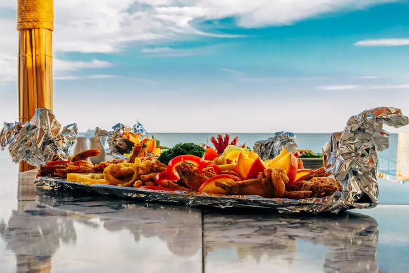 Assiette de fruits de mer colorée présentée sur une table avec vue sur la mer.