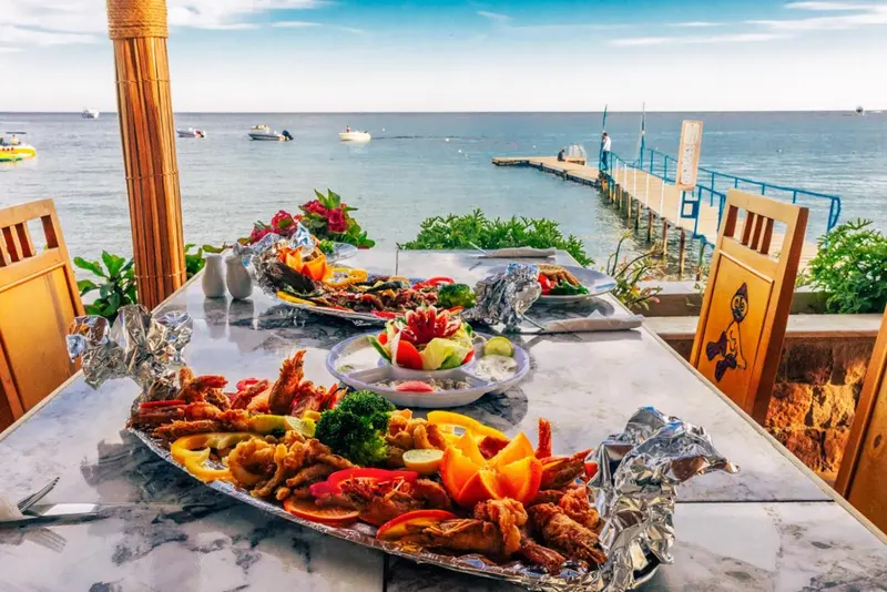 Une table dressée avec un plateau de fruits de mer colorés en extérieur.
