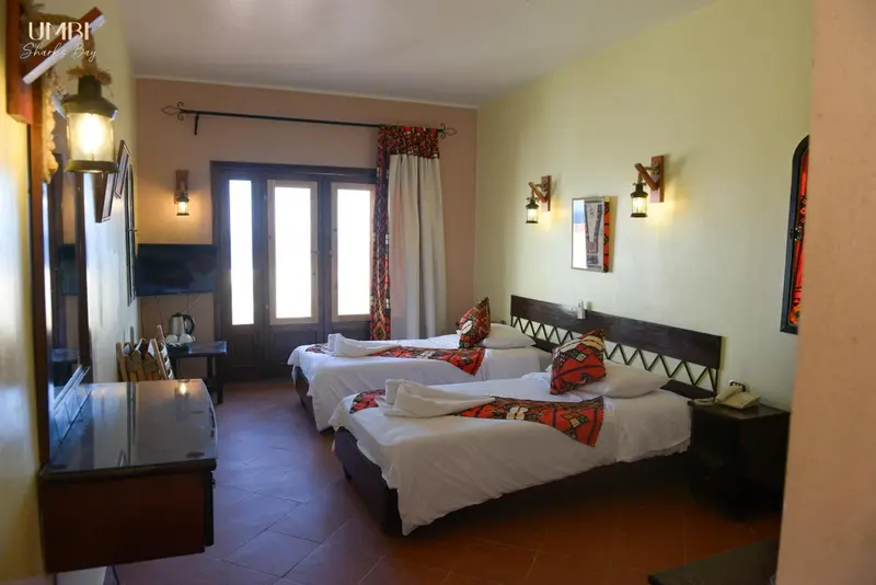 Chambre lumineuse avec deux lits simples et décoration murale.