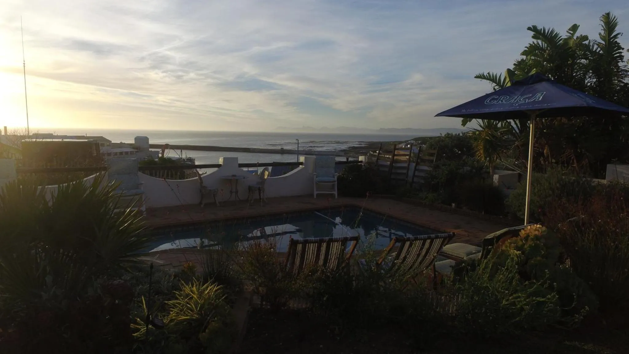 Terrasse avec piscine et vue sur la mer au coucher du soleil.