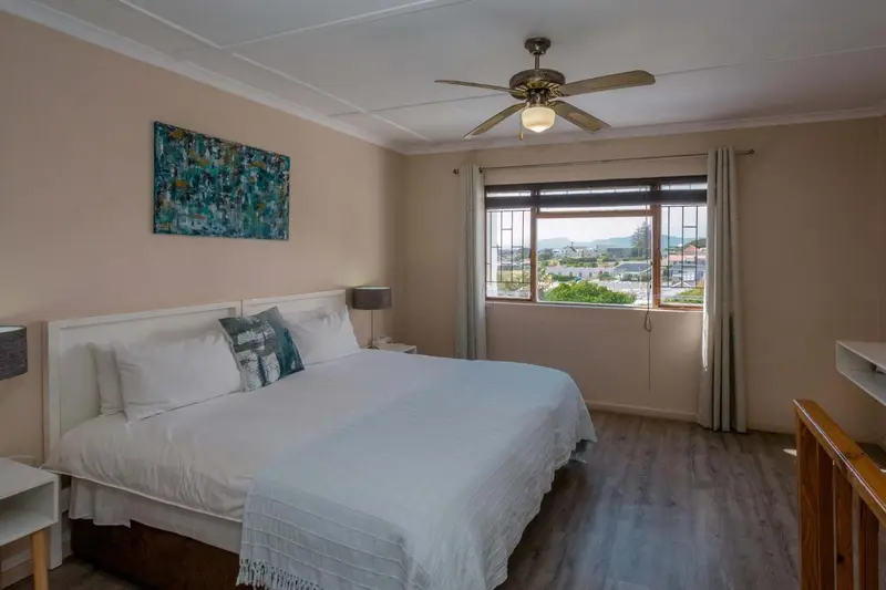 Une chambre lumineuse avec un grand lit recouvert d'une courtepointe blanche et bleue.
