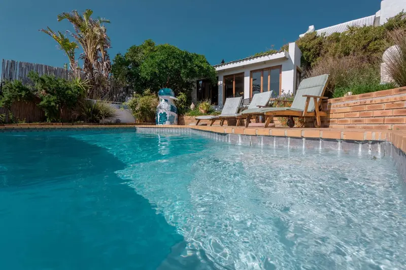Une piscine turquoise bordée d'une terrasse avec des chaises longues.
