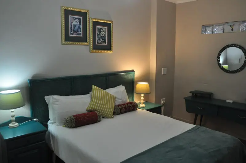 Une chambre lumineuse avec un lit recouvert d'oreillers décoratifs.
