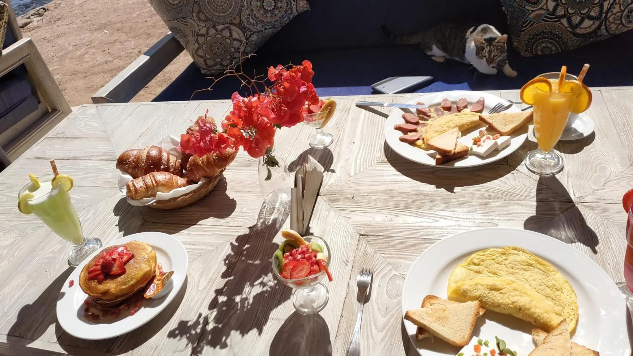 Une table est dressée avec un petit-déjeuner copieux et des boissons fraîches.