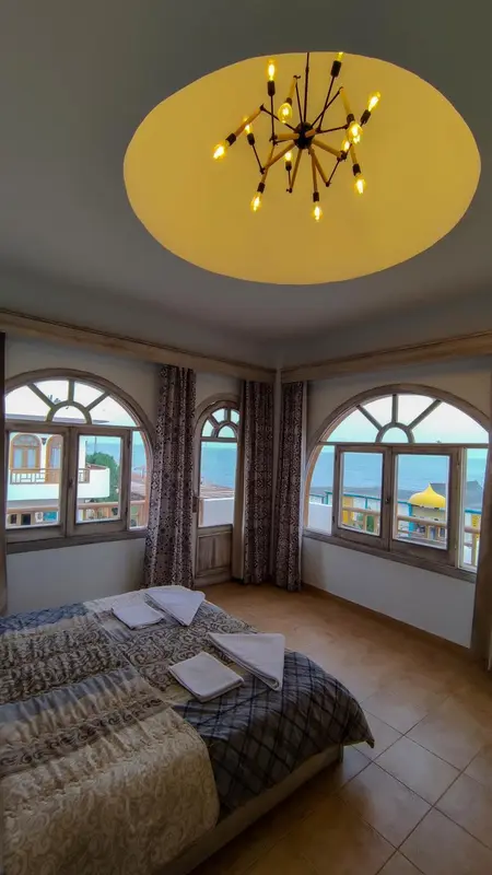 Une chambre lumineuse avec un lit fait et vue sur la mer.