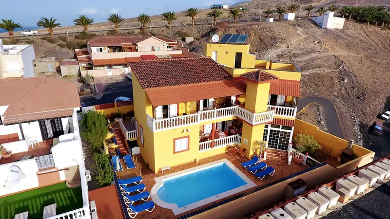 Vue aérienne d'une résidence jaune avec piscine et transats.