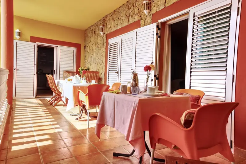 Une table est dressée pour le petit-déjeuner sur une terrasse carrelée.