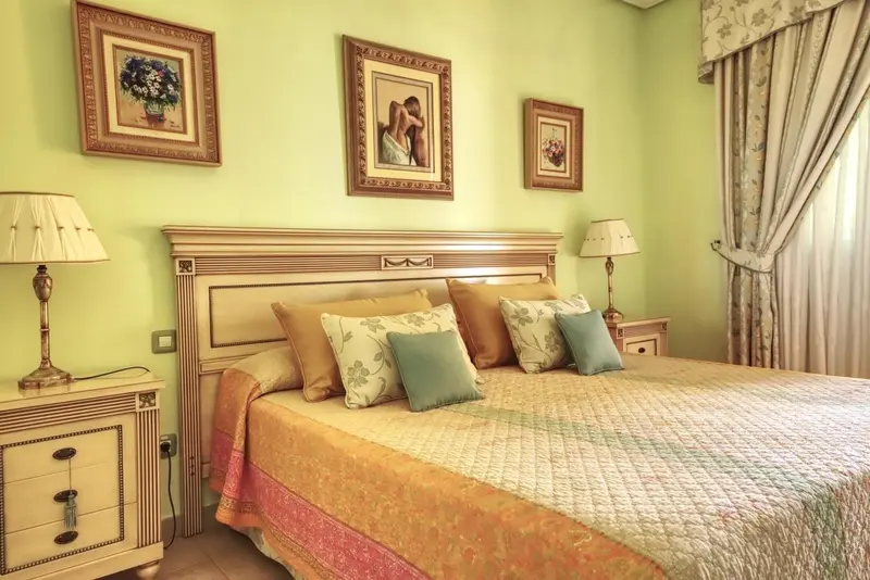 Une chambre lumineuse avec un grand lit décoré de coussins.