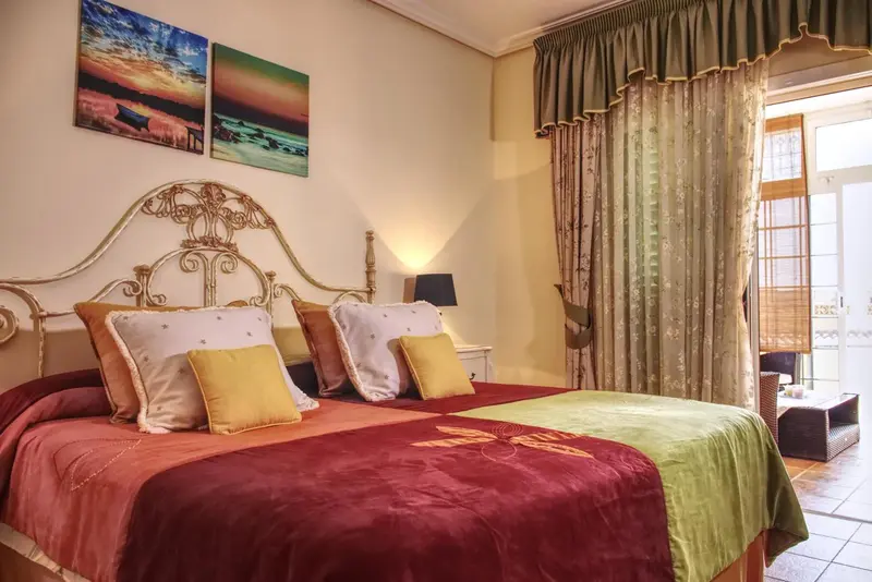 Une chambre à coucher avec un grand lit décoré de coussins et de rideaux.