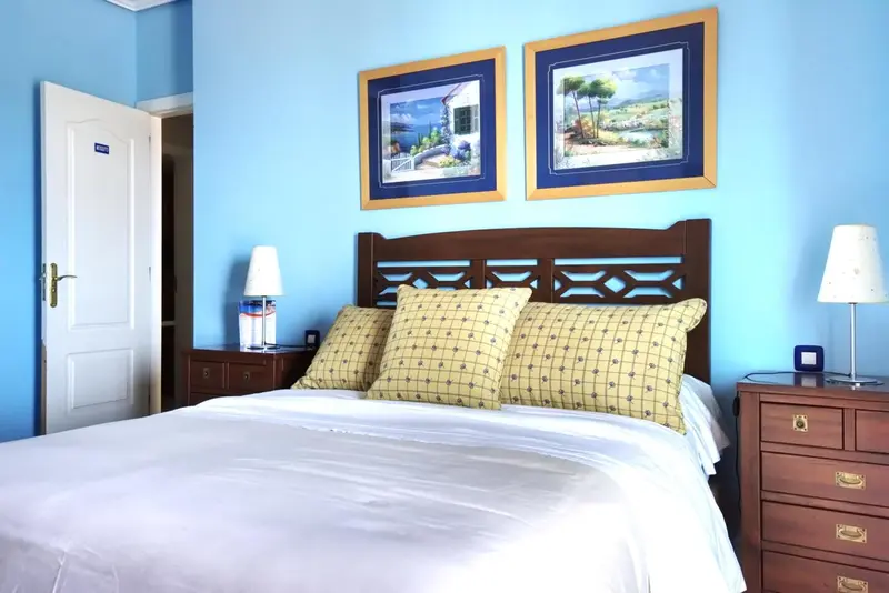 Une chambre lumineuse avec un grand lit recouvert d'une courtepointe blanche.