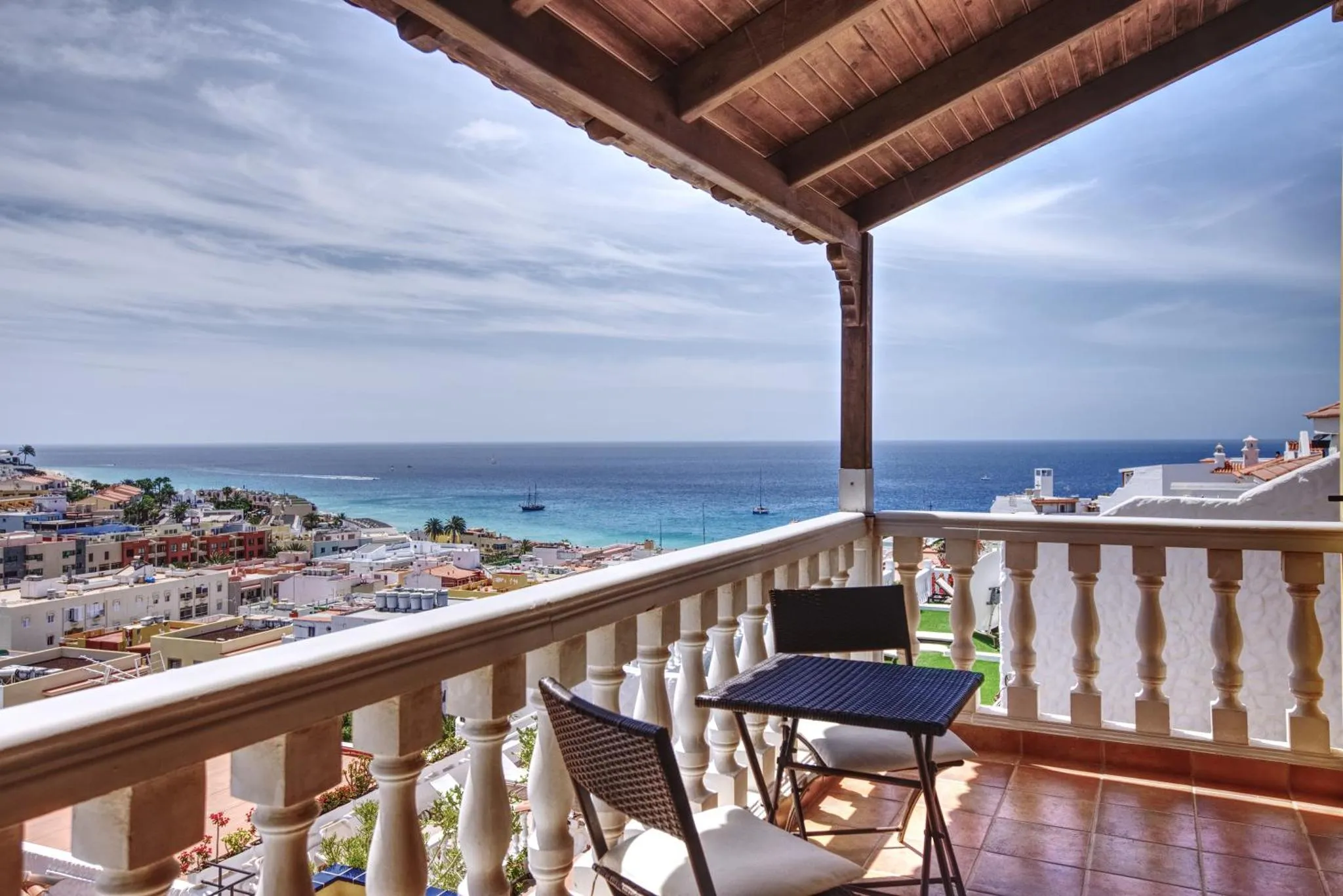 Terrasse avec mobilier donnant sur une vue mer et une ville côtière.