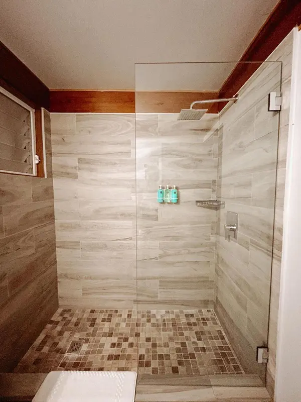 Une douche à l'italienne carrelée avec un pommeau de douche au plafond.