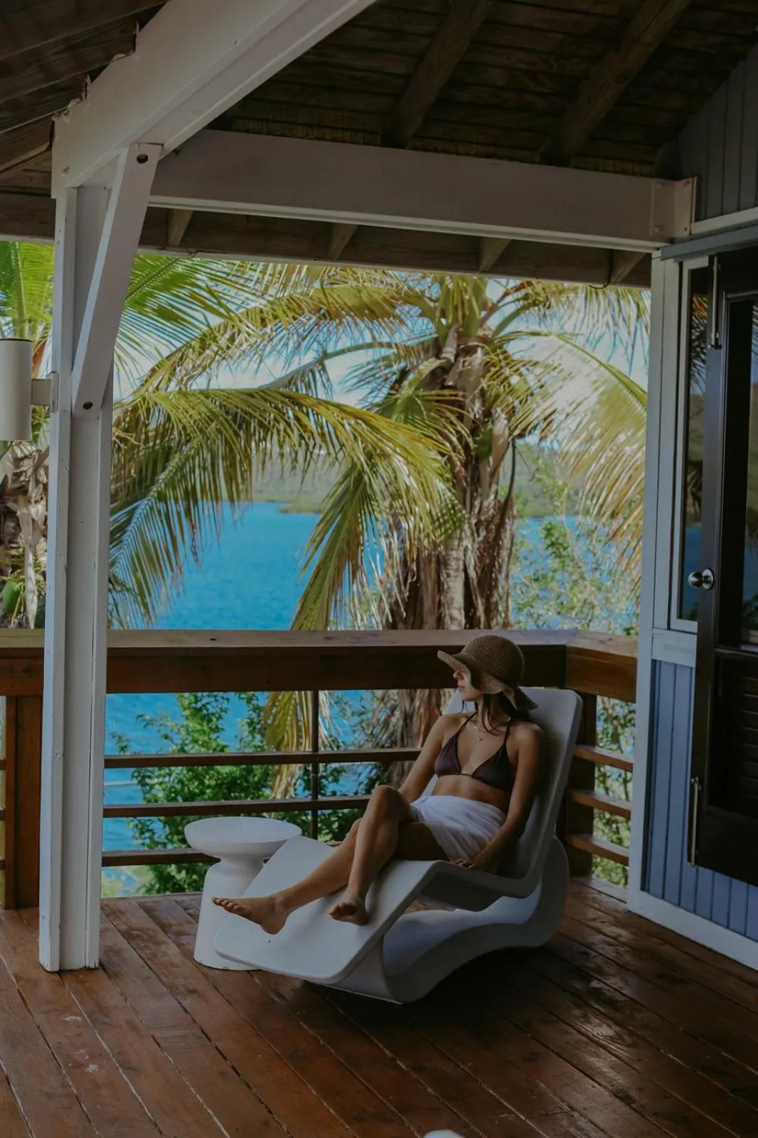 Une femme se détend sur une terrasse en bois face à la mer.