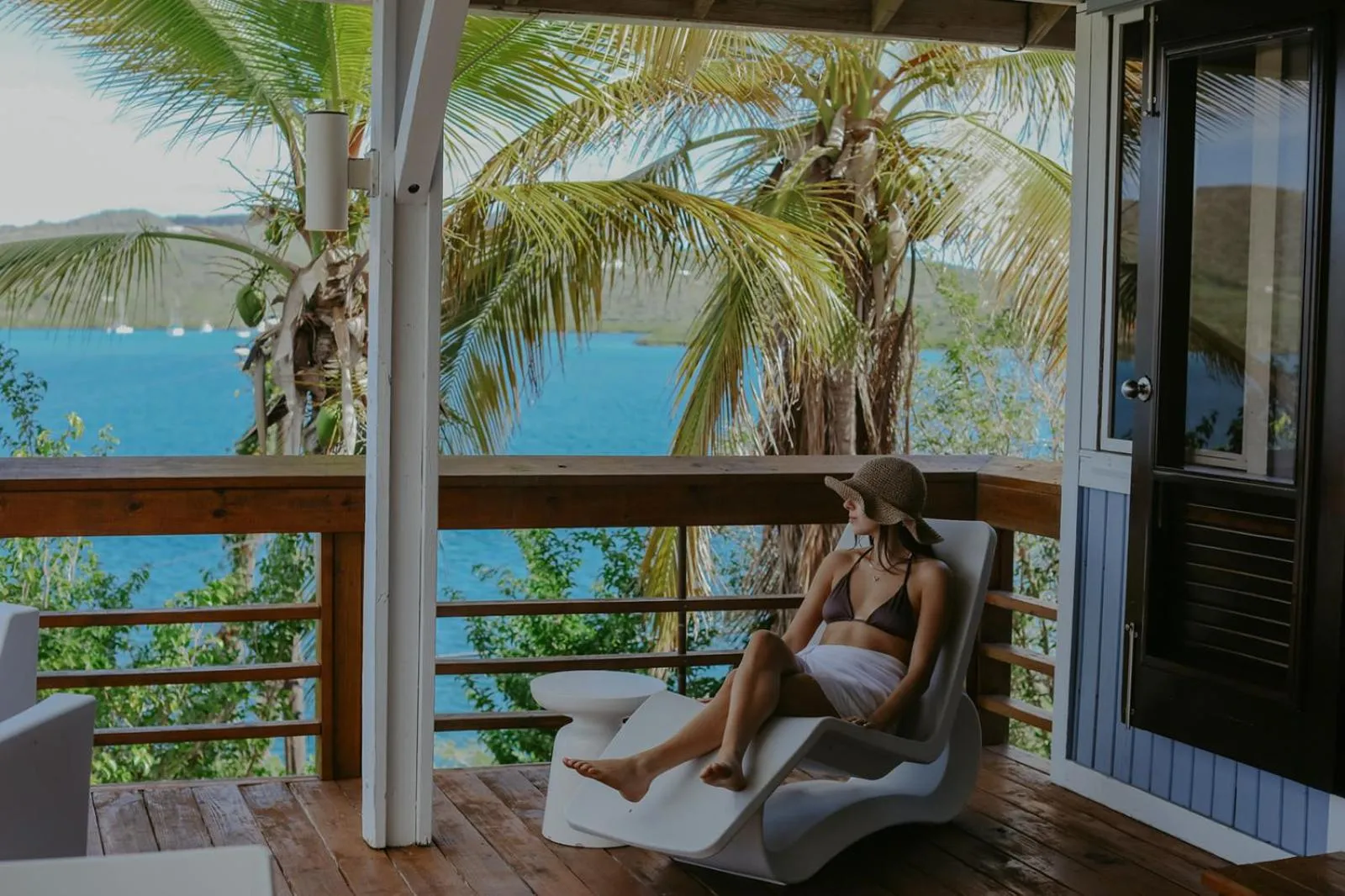 Une personne se relaxe sur une terrasse en bois avec vue sur la mer.