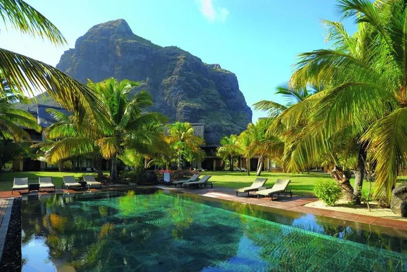 Une piscine turquoise reflète le ciel et la végétation luxuriante.