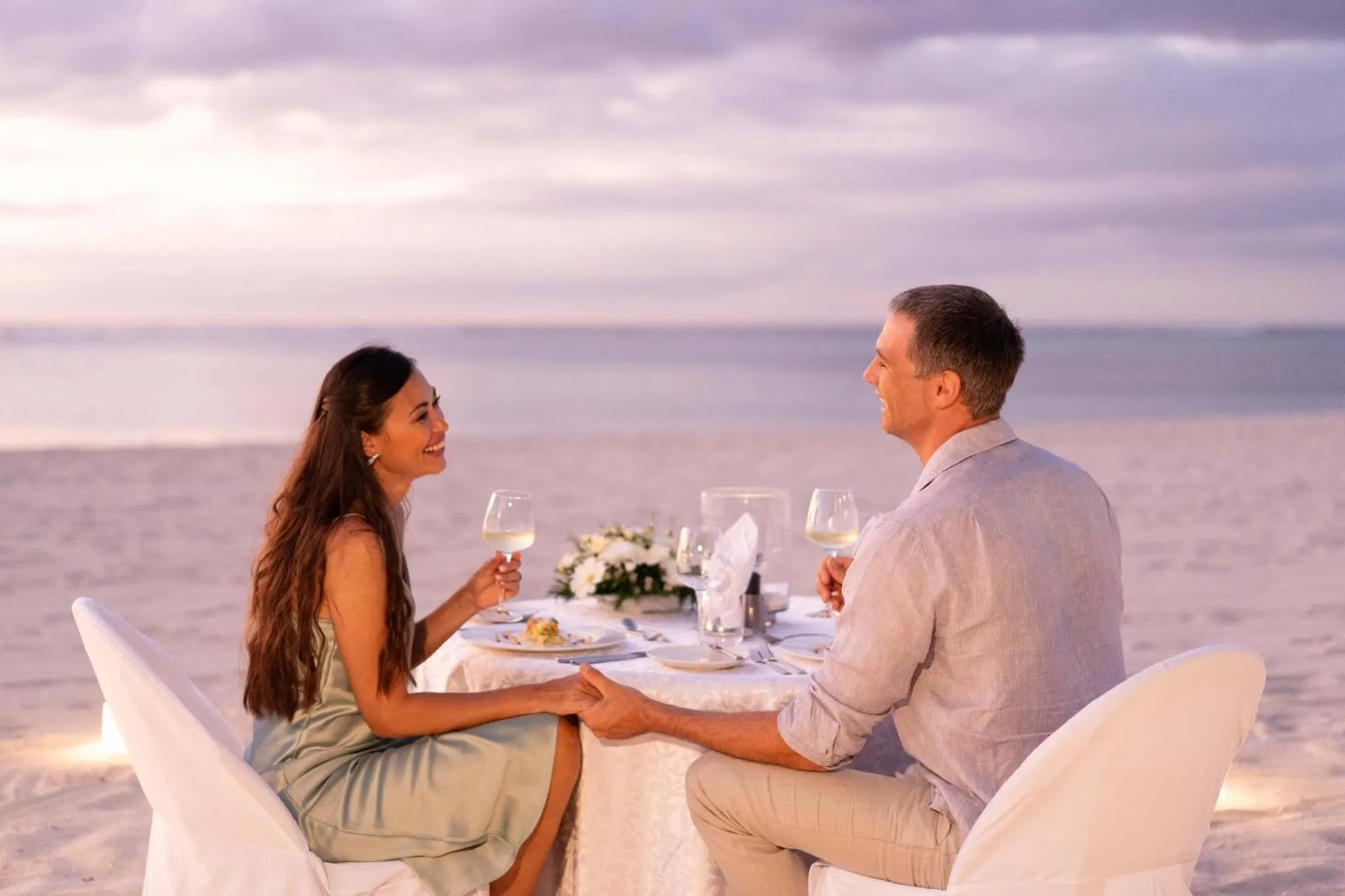 Un couple partage un repas en bord de mer au coucher du soleil.