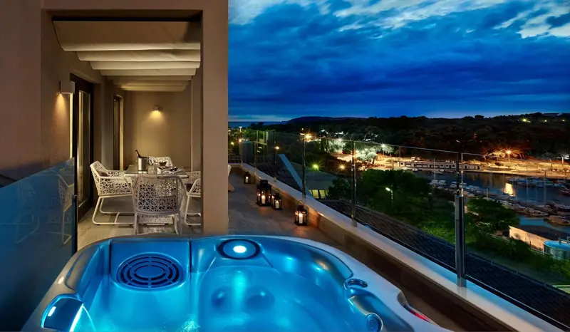 Terrasse avec jacuzzi et vue sur un port illuminé au crépuscule.