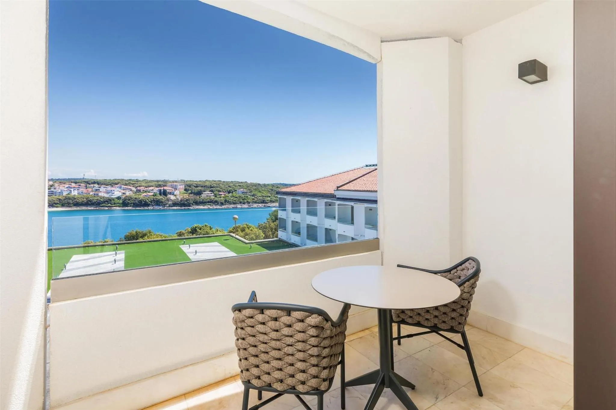 Une terrasse avec une table et des chaises offre une vue sur la mer et la ville.